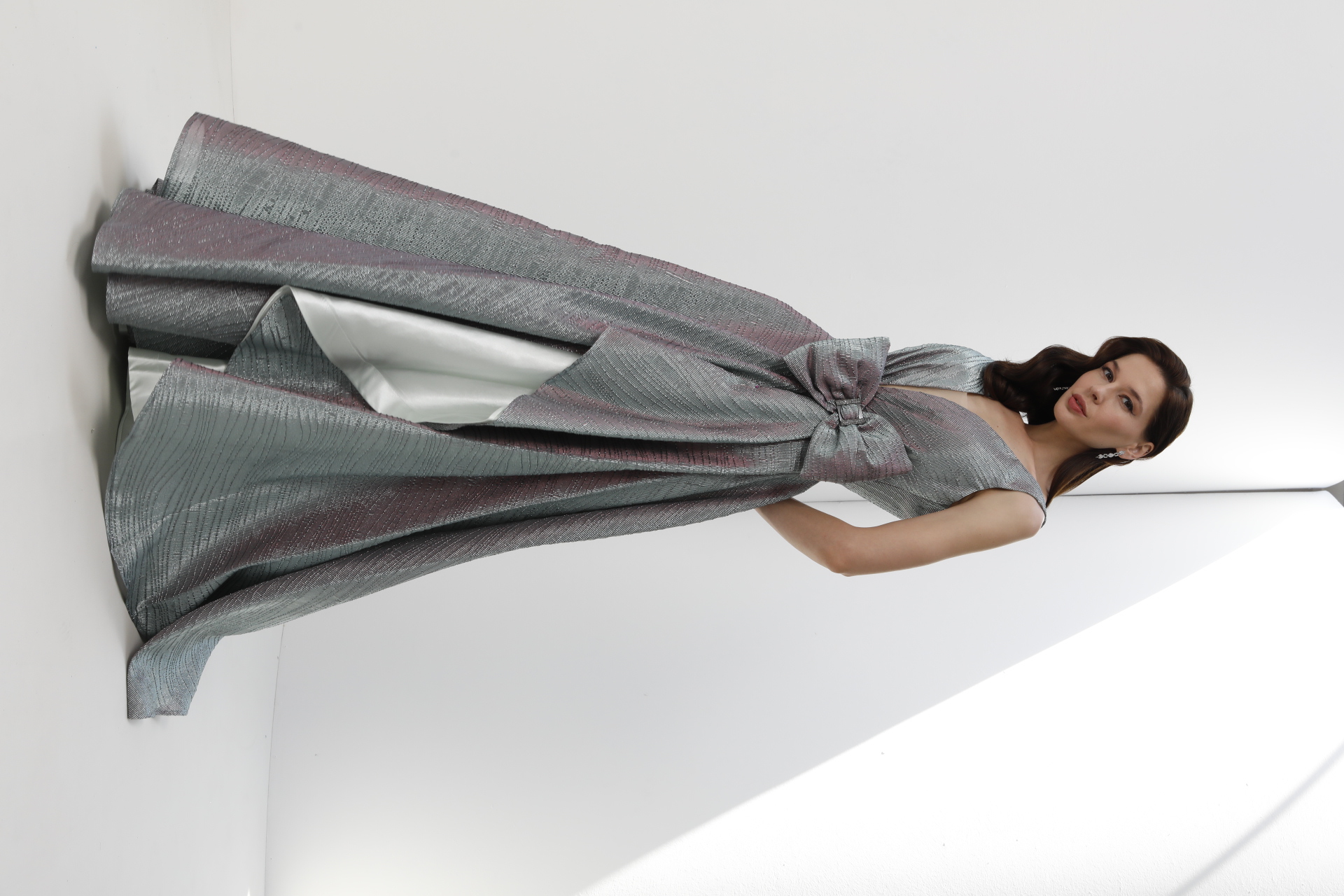 Silver iridescent metallic gown with oversized bow and high-low pleated skirt