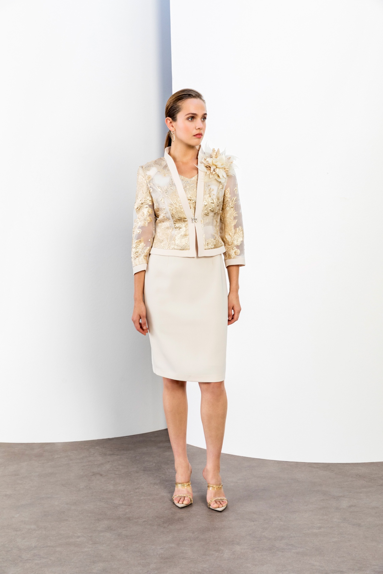 Ivory pencil dress with gold brocade jacket and feather corsage