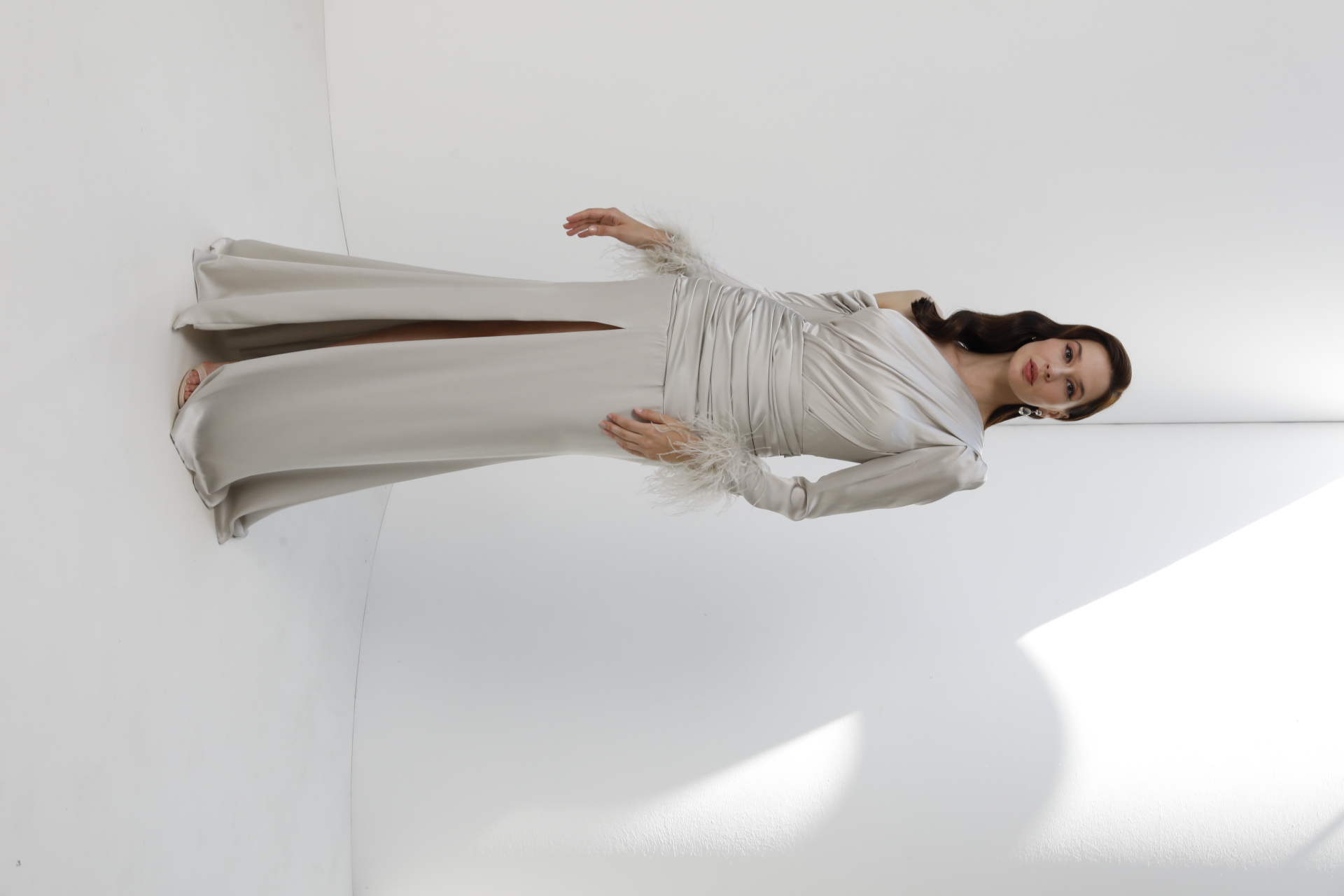 Silver satin one-shoulder gown with feather cuff sleeves and side slit