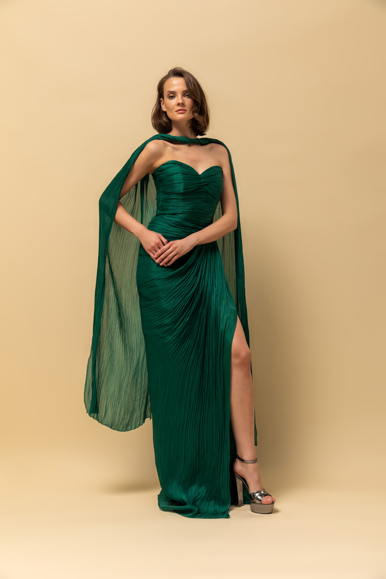 Emerald green pleated chiffon strapless gown with cape sleeves and high slit
